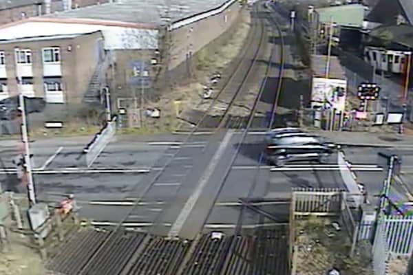 A car ignoring the signals and crossing the other side of the road to quickly dodge the closing barriers (Langley Green level crossing, West Midlands).  