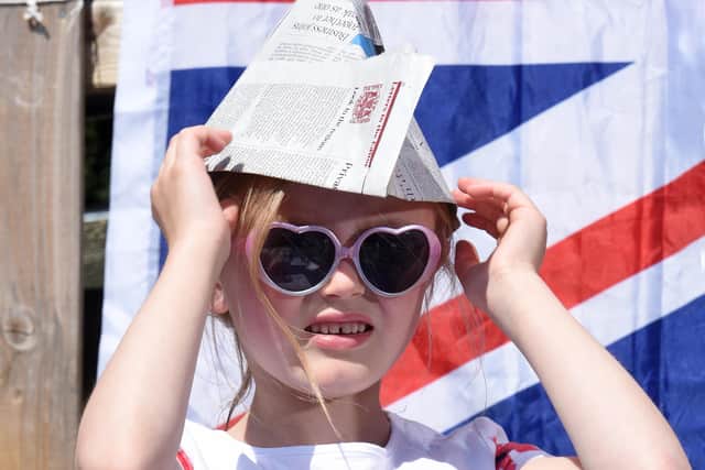 Ariana Malone adjusts her hat made from a newspaper as protection from the sun at a VE Day anniversary picnic at Shelf Junior and Infants School, Halifax, which remains open for around eight children of key workers.
