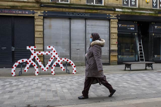 31 March  2020 .....   A  shopper masked for protection  passes a Tour de Yorkshire red polka dot decorated cycle rack in Halifax town centre during the coronavirus lockdown.  The prestigious bike race has been postponed. Tony Johnson