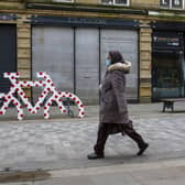 31 March  2020 .....   A  shopper masked for protection  passes a Tour de Yorkshire red polka dot decorated cycle rack in Halifax town centre during the coronavirus lockdown.  The prestigious bike race has been postponed. Tony Johnson