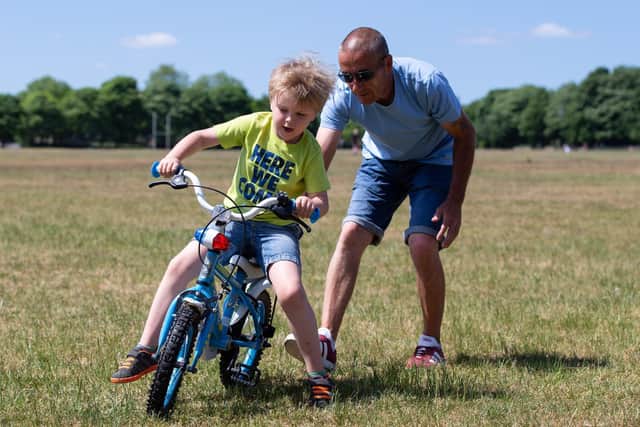 Nick Mallinson helps Harley, six years old, learns to ride his bike on Savile Park, Halifax