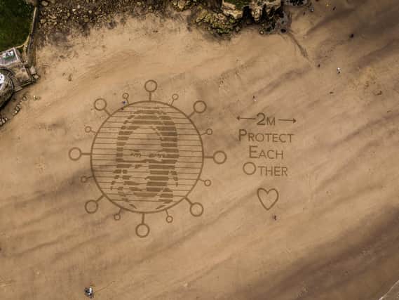 Beach art urging people to visit Whitby, and other resorts, responsibly.