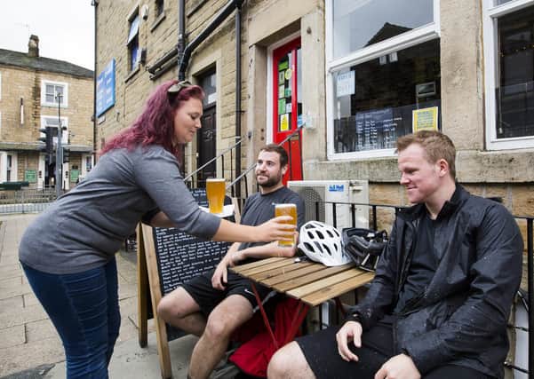 Lea McCarthy, who is exempt from wearing a face covering, serves customers James Rosthorn, left, and Liam Garrigan at The Pub, Todmorden.