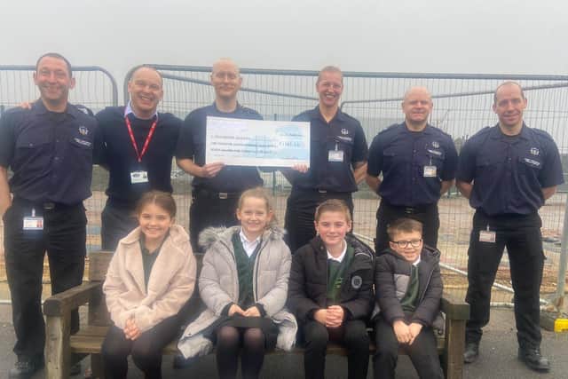 Youngsters from Ash Green Primary School with Illingworth firefighters who were first on scene and raised money for the school by holding a car wash.