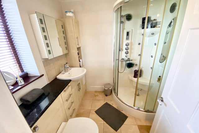 A corner shower with seat, and fitted units within this facility.