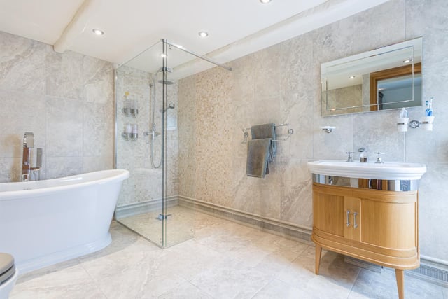 A deep bath tub, walk-in shower and wash basin with vanity unit all feature within this stunning bathroom.