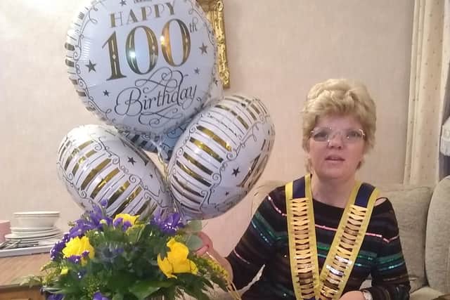 Club President, Caroline Pell holding celebratory balloons with flowers presented by the Inner Wheel Club of Halifax.