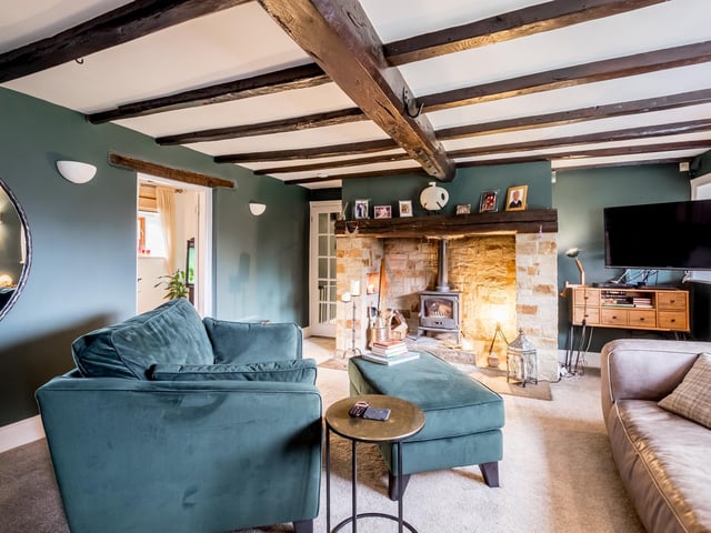 Beams to the ceiling and a rustic fireplace with stove make this a warm and welcoming room.