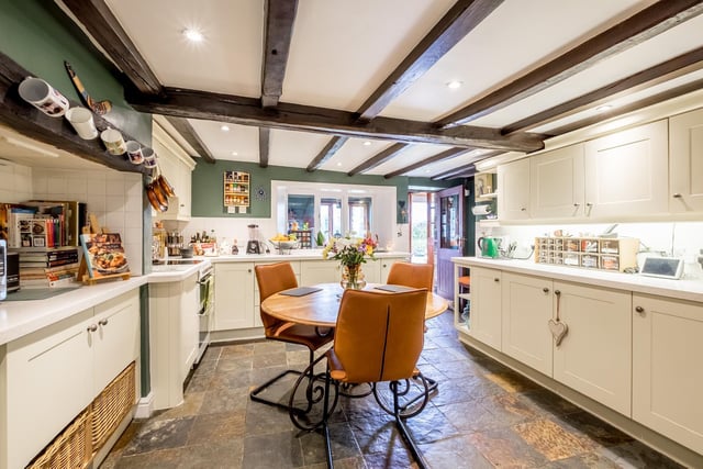 A bright farmhouse kitchen with a vast array of fitted units and access to outdoors.