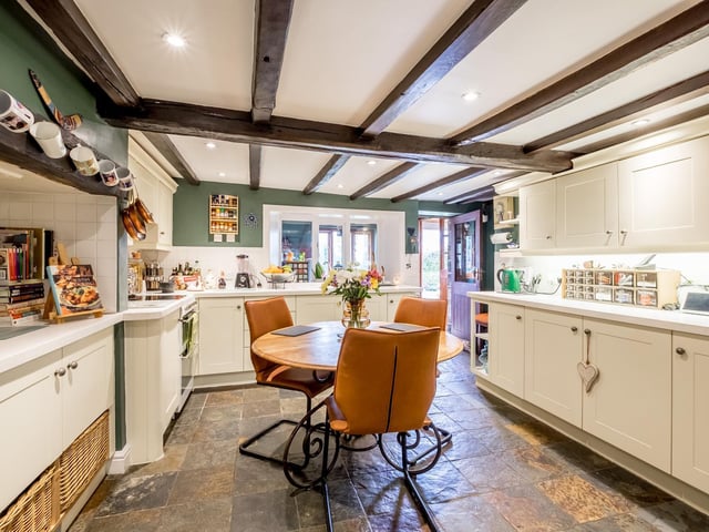 A bright farmhouse kitchen with a vast array of fitted units and access to outdoors.