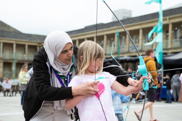 Five-year-old Abbeigh Gelder trying archery with help from Sajida Kauser from 51st Pellon Scouts
