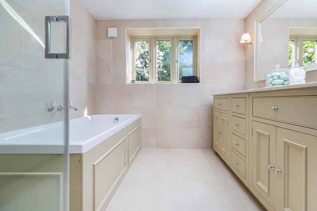 The stylish house bathroom includes both bath and shower, with twin wash basins set within an extended vanity unit.