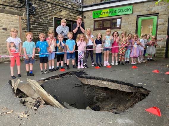 Members of Limelight Theatre school with a huge sink hole outside their building