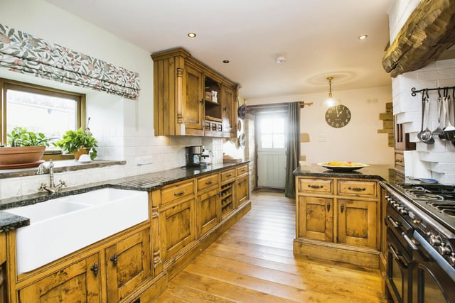 The dining kitchen has solid wood units with granite worktops, a range oven, wooden floor, and dining area with a stone fireplace.