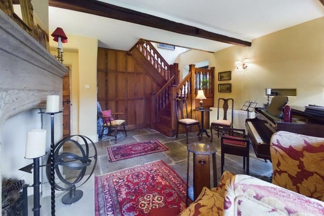 Wooden panelling is a feature to one wall of this beamed music room with a solid oak staircase leading up.