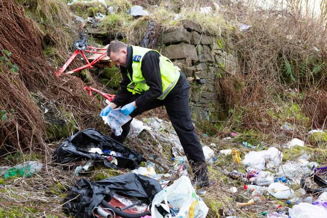 A Calderdale Council  community safety Warden inspects rubbish at a fly tipping hot spot in Halifax on an anti-social behaviour enforcement patrol.