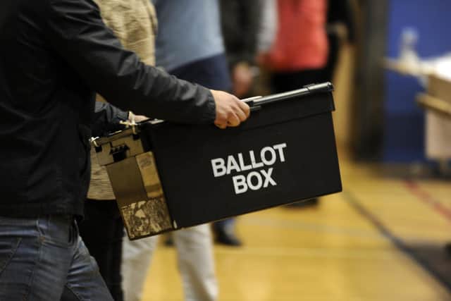 Ballot boxes are carried into a hall ready for the counting of votes at an election.