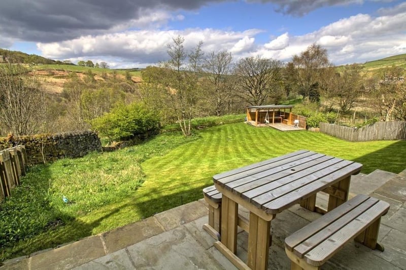 A lawned and sloped garden with far reaching views, and decked patio seating areas.