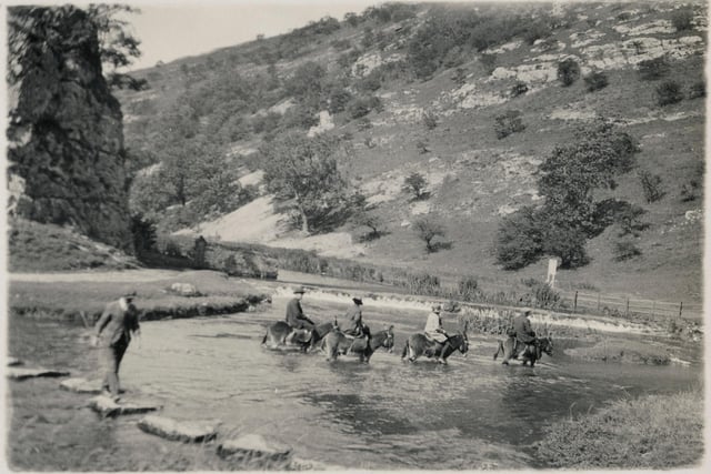 People on horseback wading across the River Dove by the stepping stones at Dovedale in the 1950s.