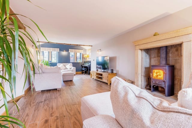 A bright and spacious living room has a stone fireplace with a Clearview multi-fuel stove.