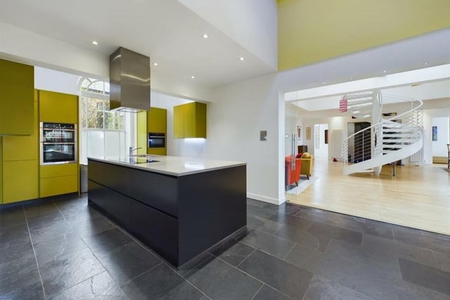 The sleek kitchen has a central island, and a bespoke range of fitted units.