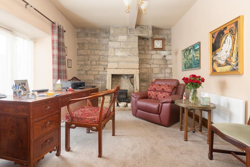 A bright and comfortable office has open stonework to one wall, with a fireplace and stove.