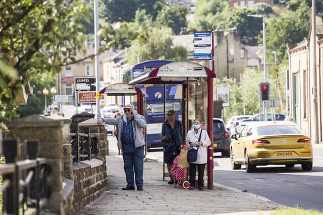 Passengers waiting at a bus stop on Huddersfield Road, Brighouse.