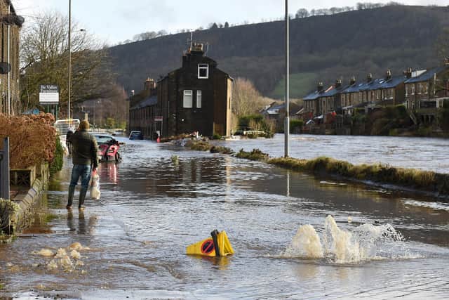 A man walks along a flooded street in Mytholmroyd, on February 9, 2020, after the River Calder burst its banks as Storm Ciara swept over the country. Photo by OLI SCARFF/AFP via Getty Images