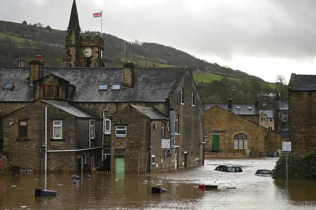 Submerged cars and floating wheelie bins are pictured in a flooded street in Mytholmroyd in 2020. (Photo by OLI SCARFF/AFP via Getty Images)