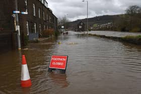 A sign reads "footpath closed" as it stands in a flooded street in Mytholmroyd, in 2020. (Photo by OLI SCARFF/AFP via Getty Images)