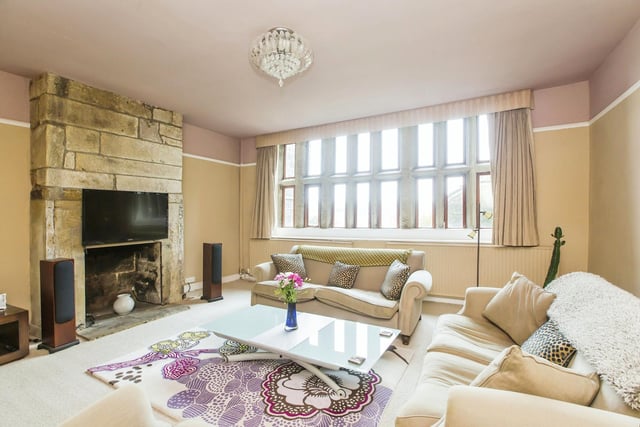 A spacious reception room with stone fireplace and mullion windows.
