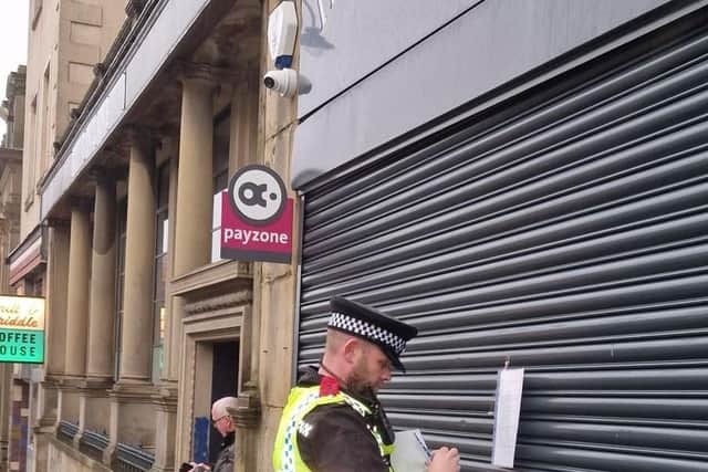 Inspector Graham, from Halifax NPT, is pictured securing a copy of the closure notice, to the store front.