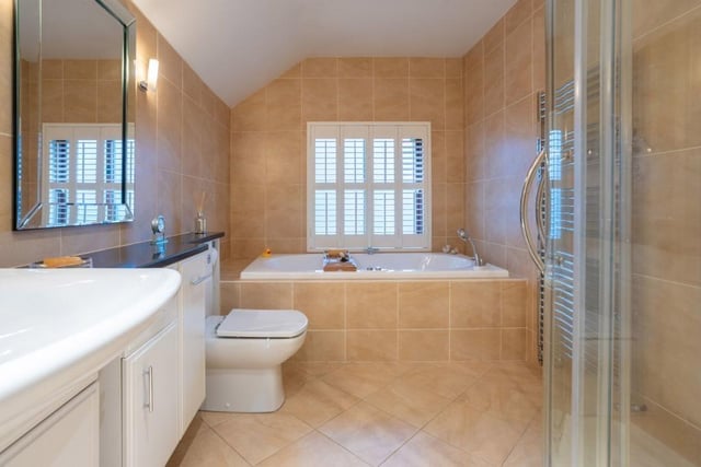 The luxurious house bathroom has a jacuzzi style bath and a walk-in shower.