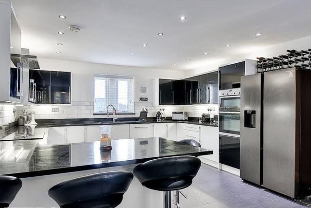 A sleek and shiny kitchen with high gloss units, granite worktops and integrated appliances.