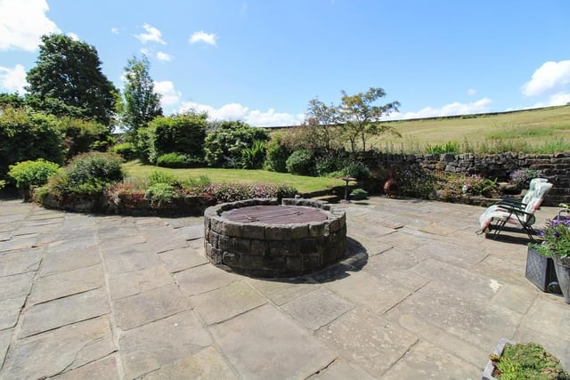 A patio with lawned garden has a raised and covered well as a feature.