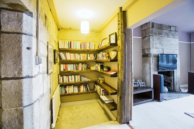 A hallway with shelving and feature stone wall.