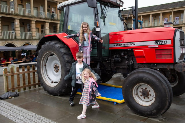 George, Lily and Ivy Stott at tractors and farm vehicles in the courtyard at The Piece Hall, Halifax