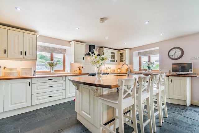 The kitchen area has bespoke painted wooden units, and a central island with breakfast bar.