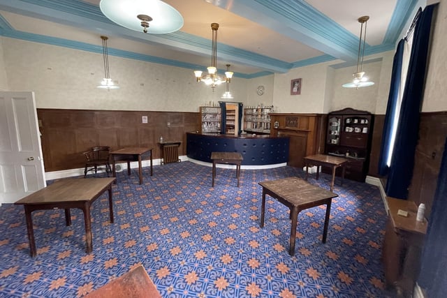 A beamed room with panelled walls and a bar.