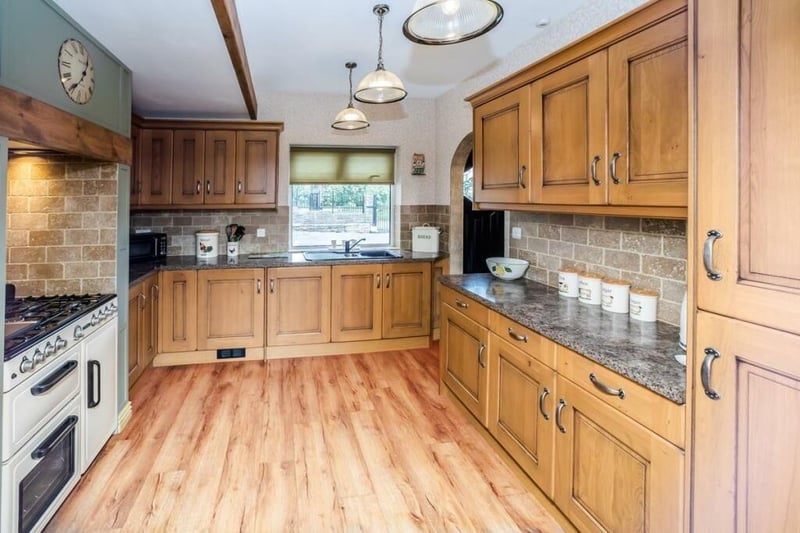 The oak kitchen has shaker style units and high range integrated appliances.