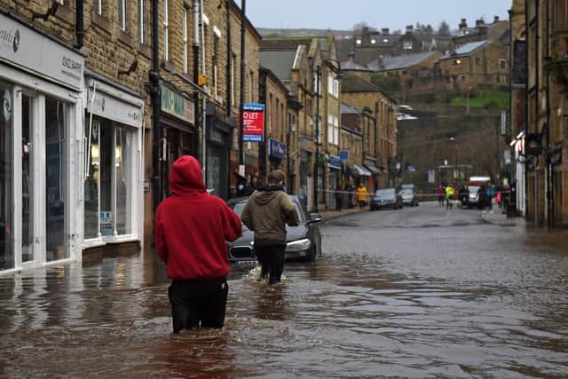 People wade through floodwater in the streets of Hebden Bridge, on February 9, 2020, as Storm Ciara swept over the country. Photo by OLI SCARFF/AFP via Getty Images