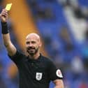 A referee brandishes a yellow card