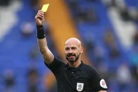 A referee brandishes a yellow card