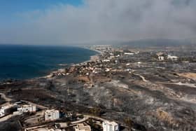 An aerial view shows smoke billowing in background of Kiotari village, on the island of Rhodes. Tens of thousands of people have already fled blazes on the island of Rhodes, with many frightened tourists scrambling to get home.