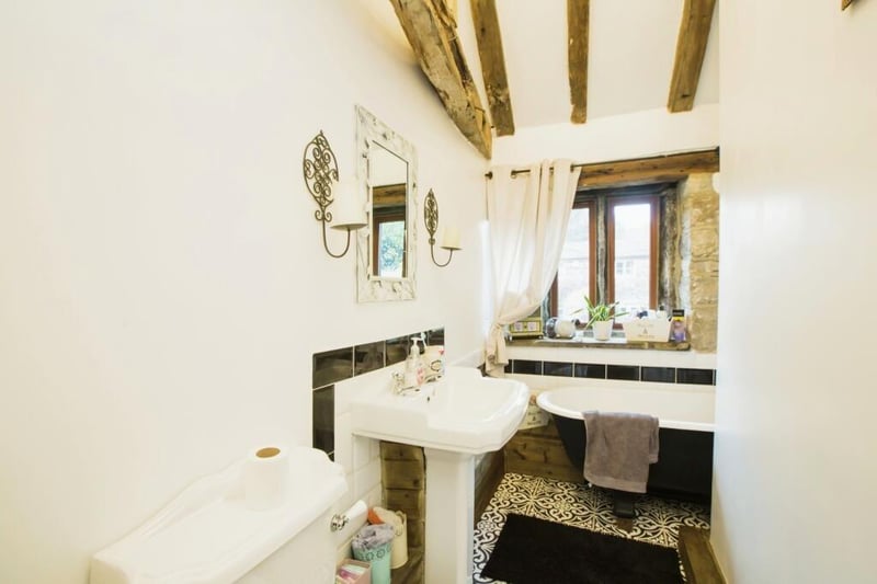 A beamed bathroom with free-standing bath tub.