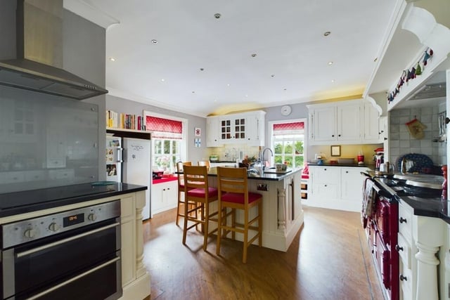 A large, red gas Aga has pride of place in the breakfast kitchen, with the painted oak units and granite worktops.