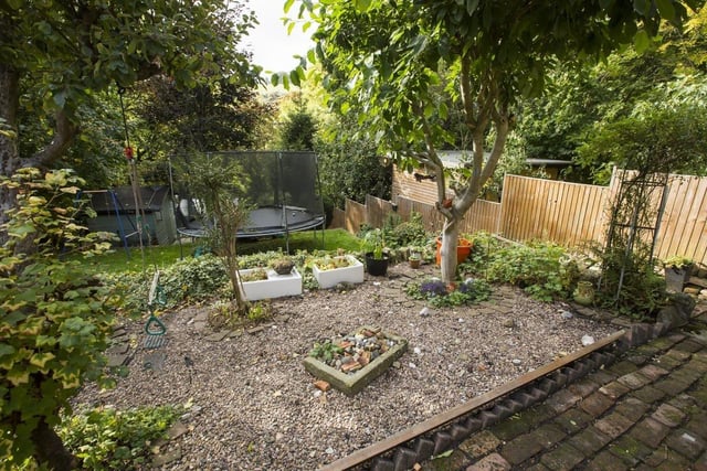 The south-facing tiered garden has lawns, seating areas and a gravelled planting area.
