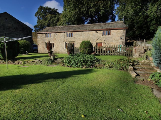 Lawned gardens stretch to the front of the 'three-in-one' cottage.