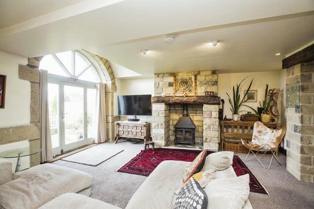 A stone fireplace with log burner, and the large arched window with door are features of the lounge.
