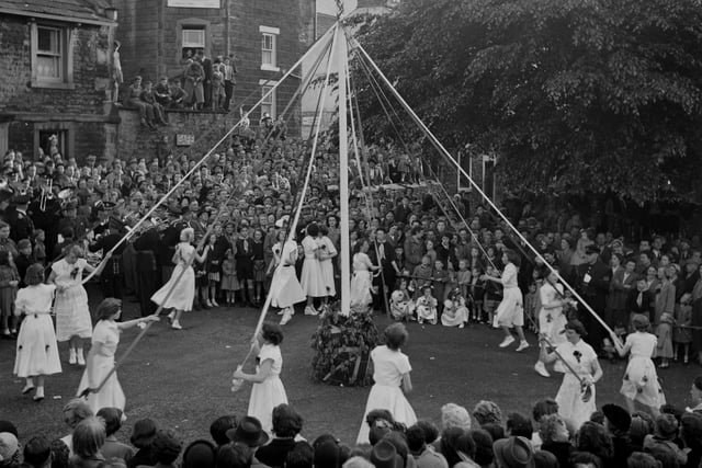 The arrival of Spring is marked in Castleton in 1950 with a festive dance around a maypole decorated with flowers and ribbons.